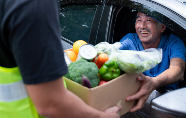 Volunteer handing a man a box of food